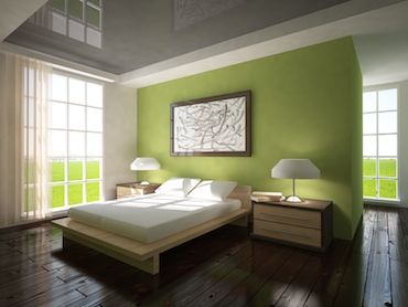 room with hardwood floor, bright windows on two sides, and a two-person bed with a bedside table and lamp on each side